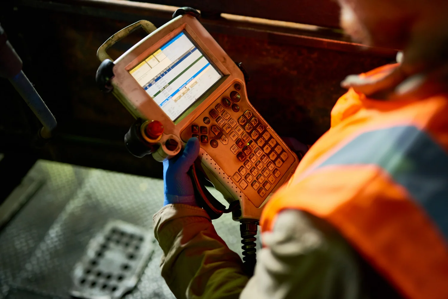 A imagem mostra um técnico manuseando um dispositivo portátil para diagnosticar e monitorar o desempenho de máquinas e sistemas mecânicos em um ambiente industrial. A cena destaca a importância da utilização de equipamentos para manutenção preditiva, visando prevenir falhas em ativos críticos de uma operação.