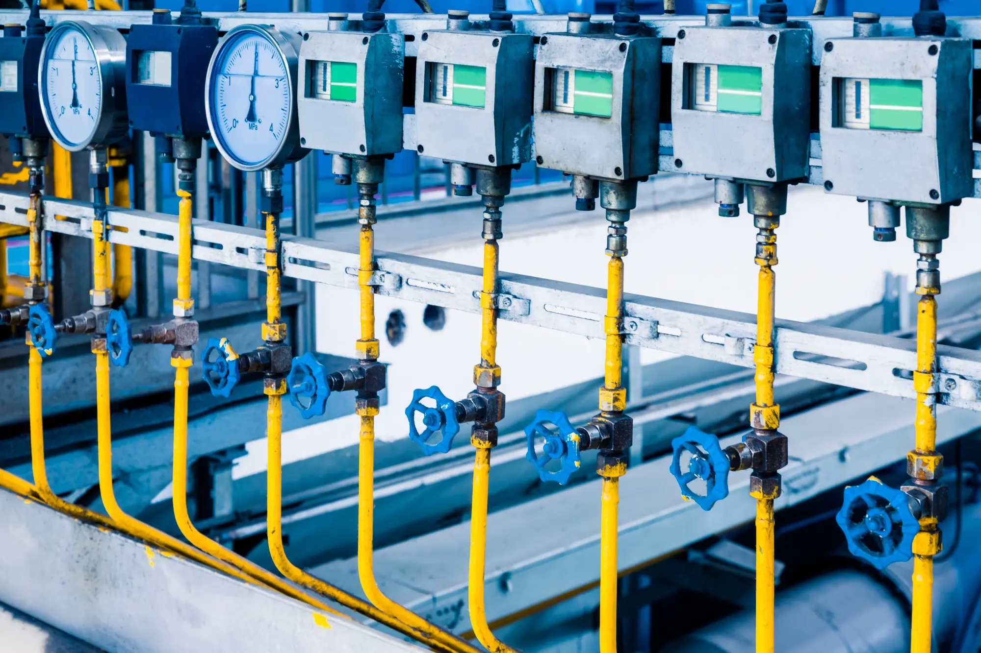 Imagem de uma planta industrial com tubos de aço amarelos e elementos finais de controle, como válvulas e atuadores.