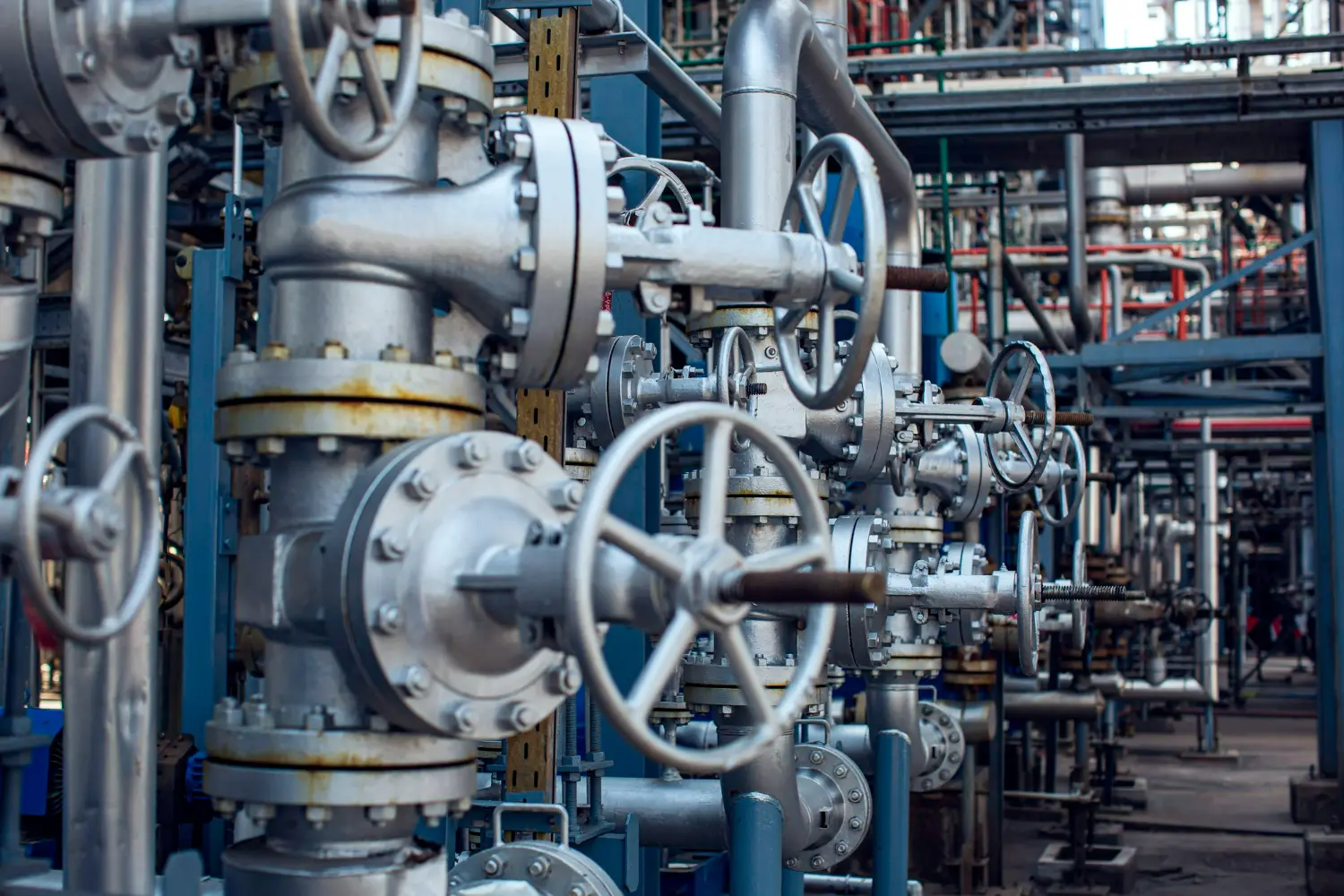 Tubulações e válvulas numa refinaria, destacando a importância de preservar a vida útil das válvulas industriais.