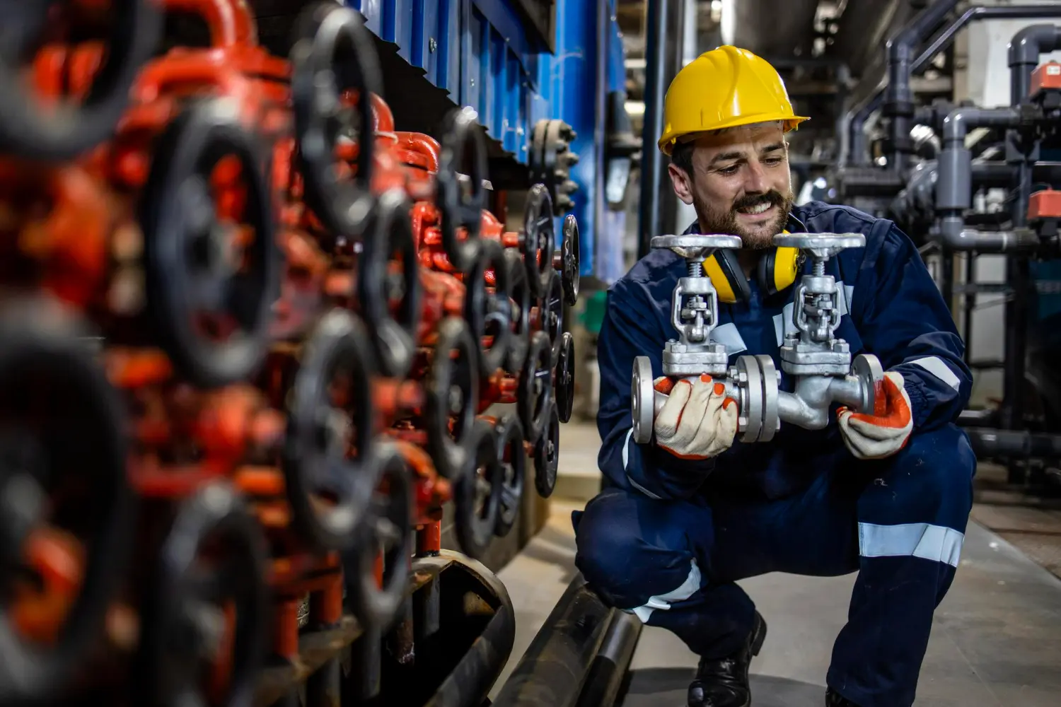 Engenheiro segurando duas válvulas, simbolizando a diferença entre válvula de controle e válvula de bloqueio.