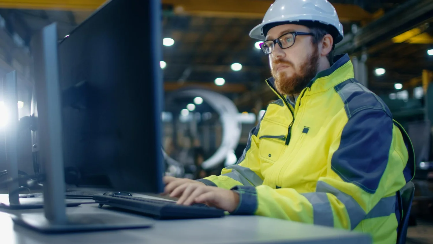 Profissional monitora equipamentos industriais em computador, reforçando a confiabilidade de ativos